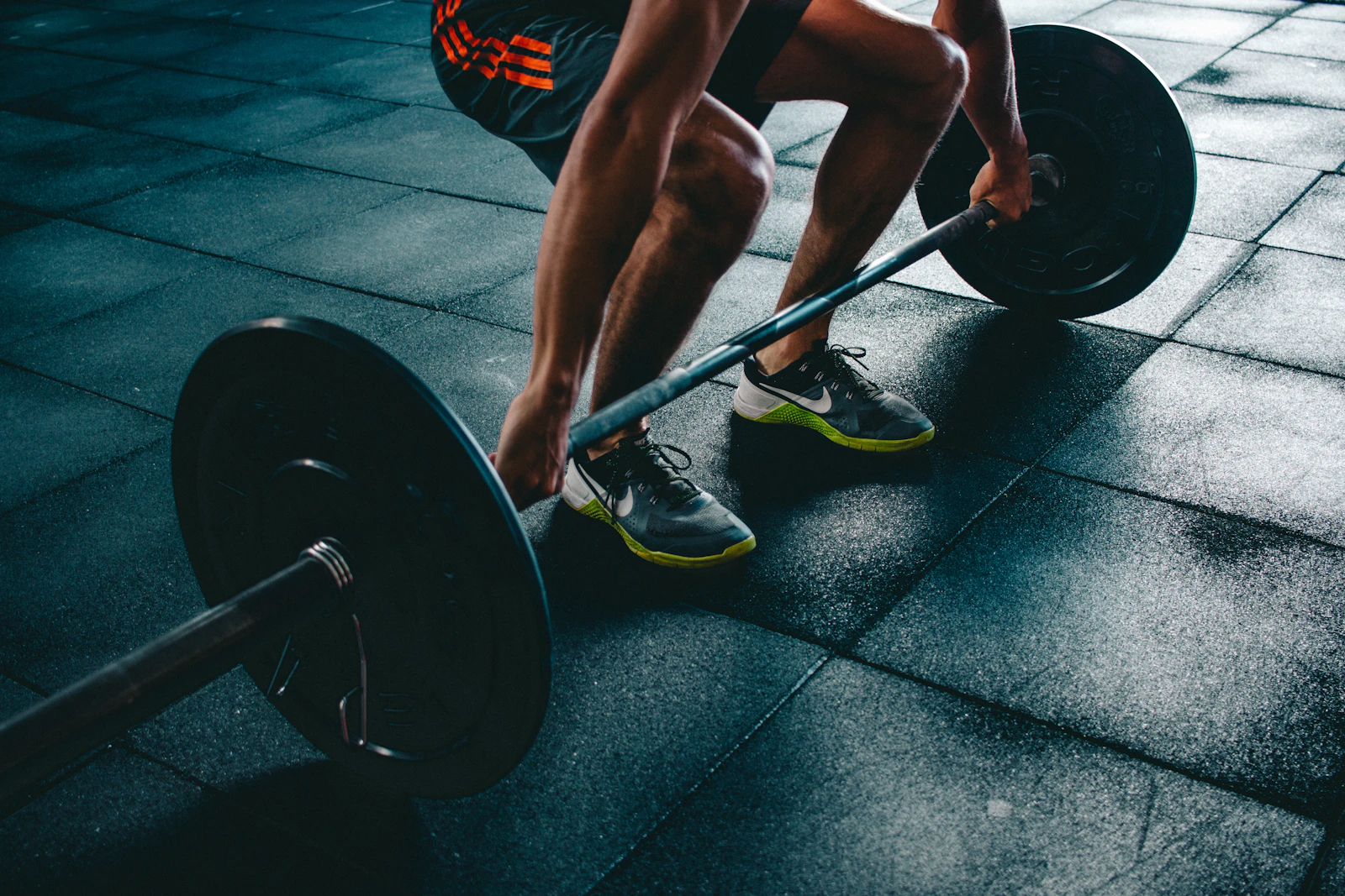 An athlete driving through a heavy barbell lift under dramatic low gym lighting