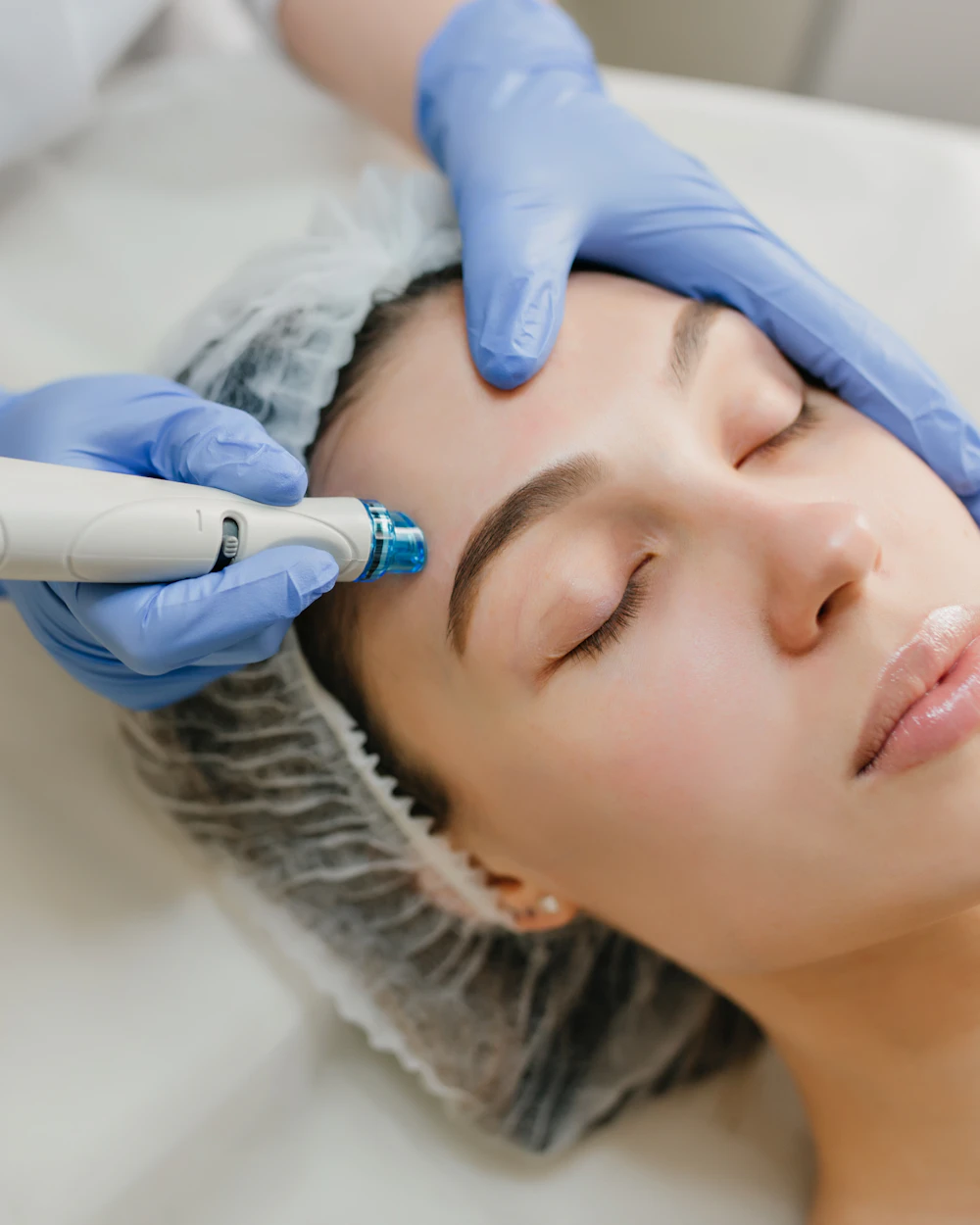 Technician using a hydrafacial-style skin device on a client's forehead