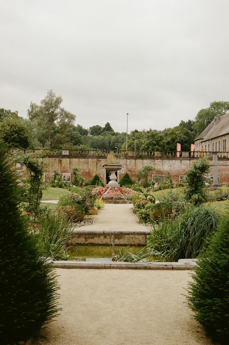 Modern stone garden pathway bordered by a stone wall and clipped hedges