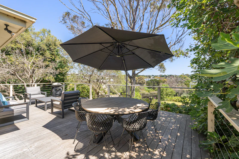 Timber outdoor patio with a dining table, chairs and a shade umbrella