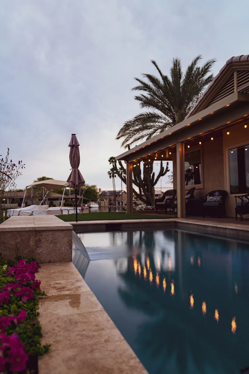 Backyard swimming pool surrounded by lush green lawn and garden beds