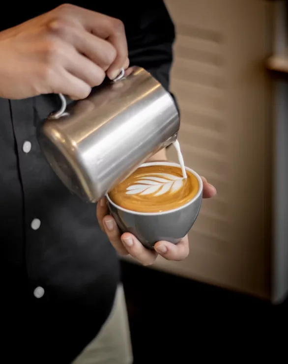 Barista pouring latte art into a cup